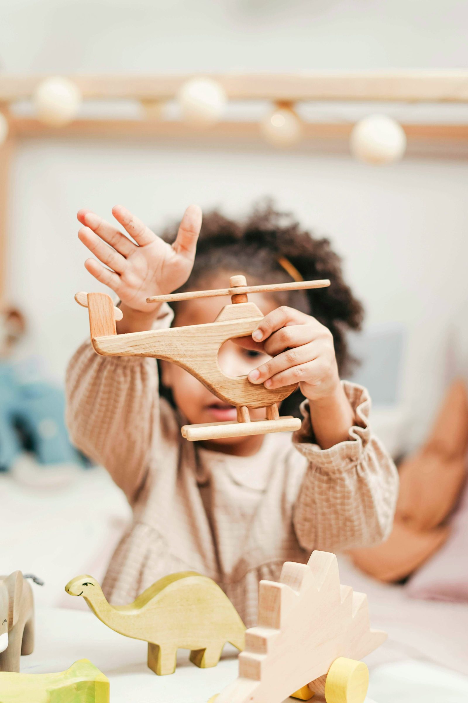 A young child holds up a wooden toy plane