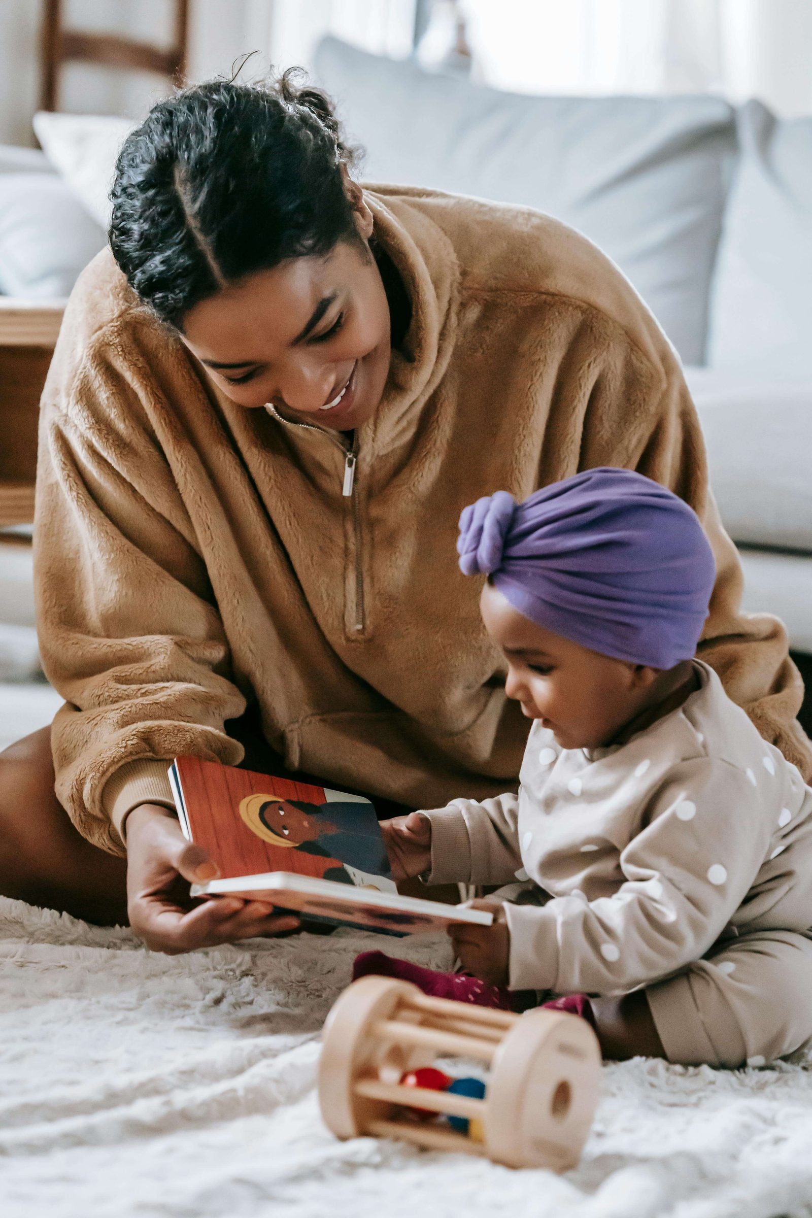 A parent and child read a picture book together on the floor