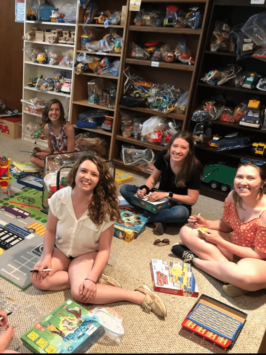 Volunteers sitting on the floor labelling toys at a toy committee work night